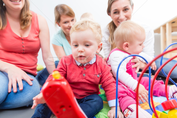 Group of happy young mothers watching their cute and healthy babies play Stock photo © Kzenon