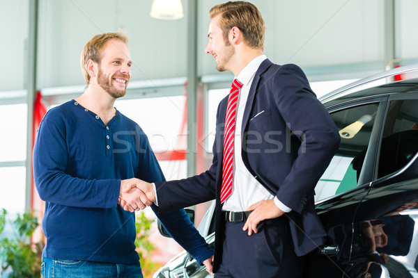 Young man and seller with auto in car dealership Stock photo © Kzenon