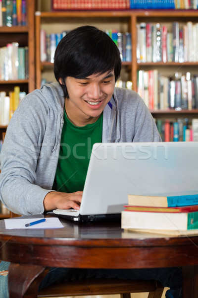 Asian man in library with laptop Stock photo © Kzenon