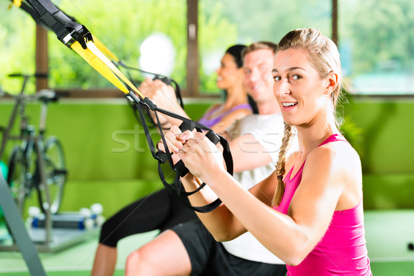 People in sport gym on suspension trainer Stock photo © Kzenon