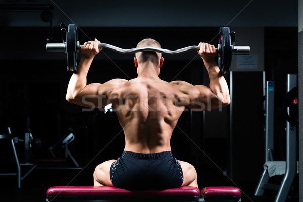 Man in gym or fitness studio on weight bench Stock photo © Kzenon