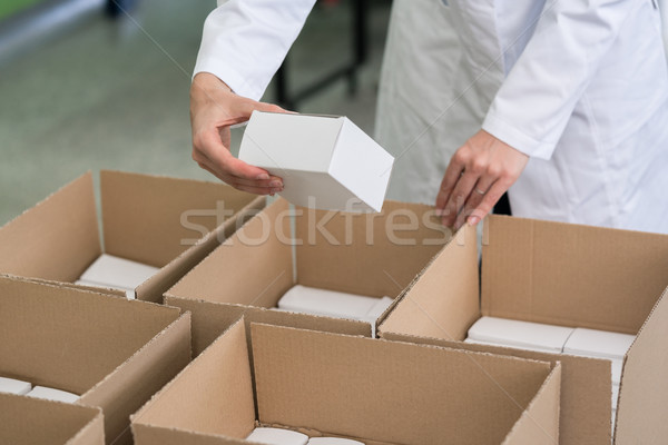 High-angle view of hands of worker putting packed products in ca Stock photo © Kzenon