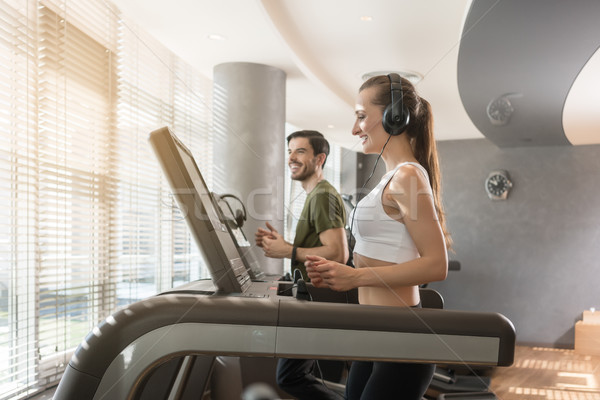Young woman listening to music while running on a modern treadmill Stock photo © Kzenon