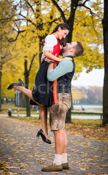 Bavarian couple in Tracht in loving embrace with uplift Stock photo © Kzenon