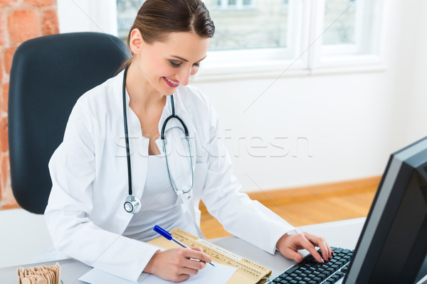 doctor at desk in clinic writing a file or dossier Stock photo © Kzenon