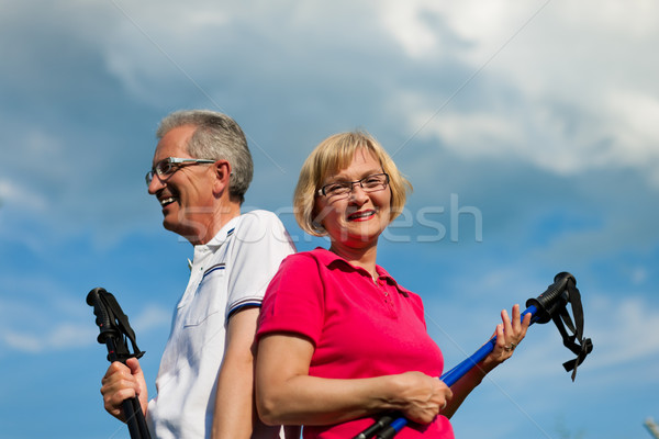 Happy mature or senior couple doing Nordic walking in summer Stock photo © Kzenon