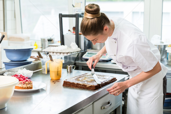Confectioner woman getting chocolate cake ready with topping Stock photo © Kzenon