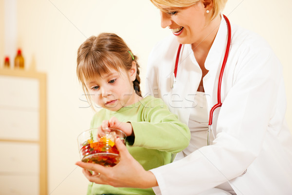 Pediatrician doctor giving candy to little patient Stock photo © Kzenon