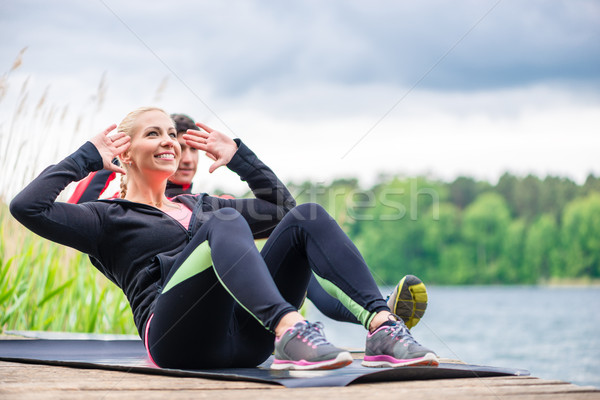 Sport couple doing sit-ups outdoor at river Stock photo © Kzenon
