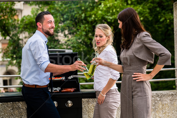 Office colleagues grilling sausages at bbq after work Stock photo © Kzenon