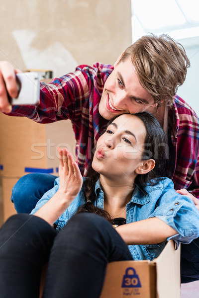 Young couple making a selfie to share the joy of moving in into  Stock photo © Kzenon