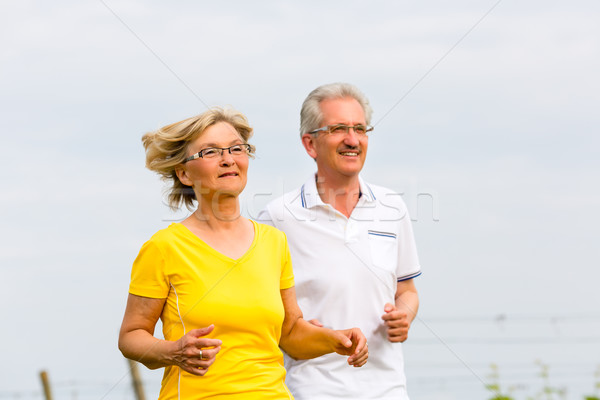 Seniors jogging in the nature doing sport Stock photo © Kzenon