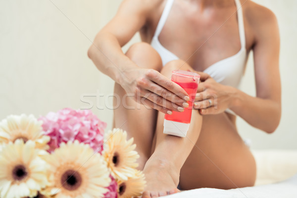 Fit woman waxing her legs with a portable roll-on depilatory wax Stock photo © Kzenon