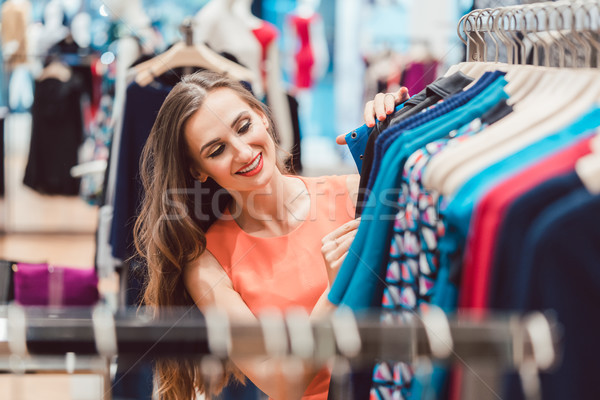 Woman browsing through dresses on rack in fashion store Stock photo © Kzenon