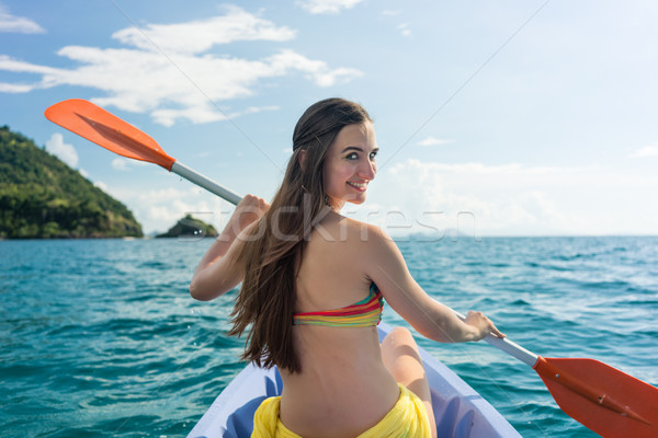 Young woman paddling a canoe on the sea during summer vacation Stock photo © Kzenon