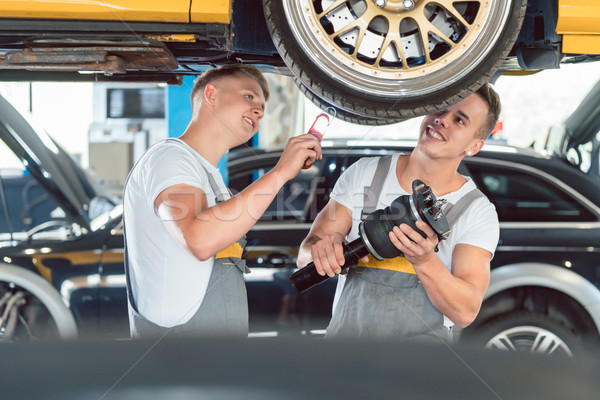 Two auto mechanics analyzing the rims of a lifted car Stock photo © Kzenon