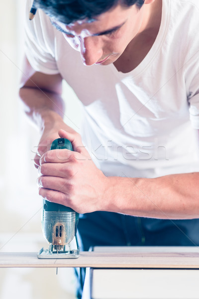 DIY worker cutting wooden panel with jig saw Stock photo © Kzenon