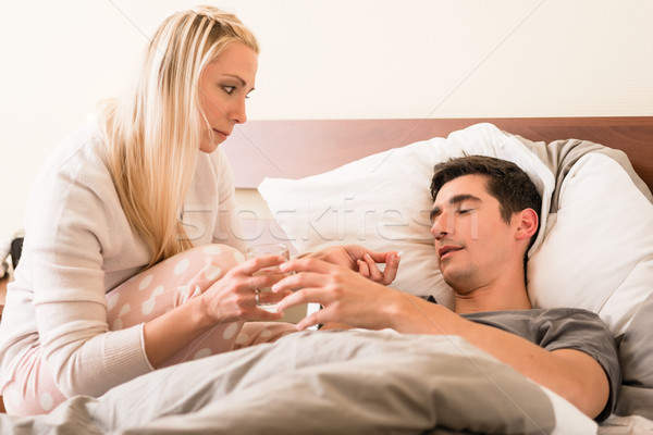 Caring young woman giving pill to her sick partner Stock photo © Kzenon