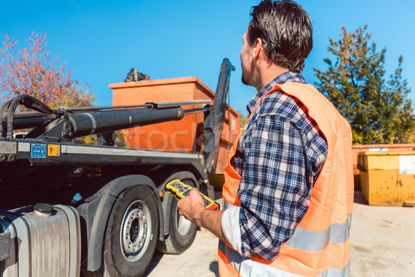 Worker on construction site unloading container for waste from truck Stock photo © Kzenon
