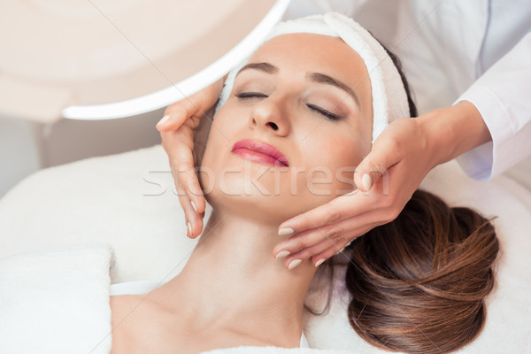 Relaxed woman smiling under the benefits of anti-aging facial massage Stock photo © Kzenon