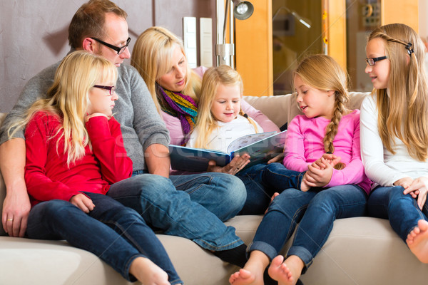 Family reading story in book on sofa in home Stock photo © Kzenon
