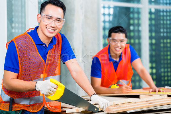 Builder sawing a wood board of building or construction site  Stock photo © Kzenon