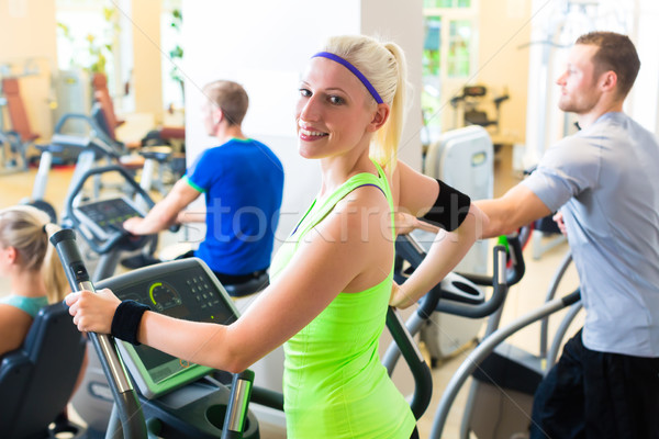 Group in gym on elliptical trainer Stock photo © Kzenon