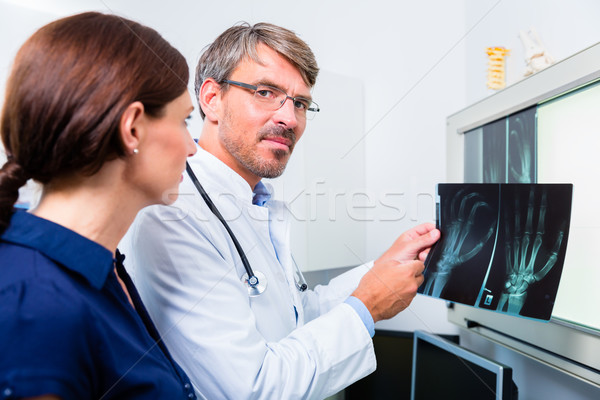 Doctor with x-ray picture of patient hand Stock photo © Kzenon