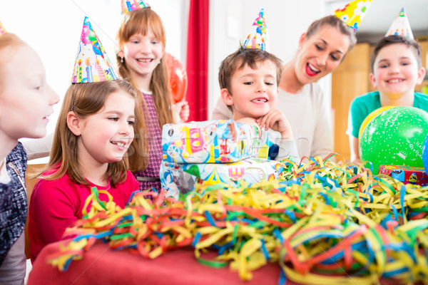 Stock photo: Child unwrapping birthday gift with friends