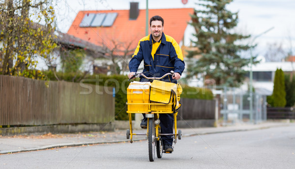 Stock photo: Postman riding his cargo bike carrying out mail in neighborhood
