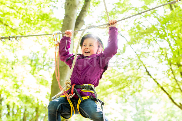 Girl climbing in high rope course Stock photo © Kzenon