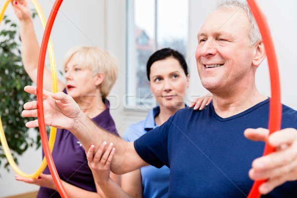 Senior couple in physiotherapy doing exercise with hula hoop Stock photo © Kzenon