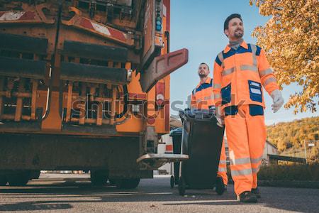 Two refuse collection workers loading garbage into waste truck Stock photo © Kzenon