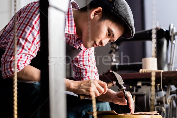 Asian shoe or belt maker in his leather workshop Stock photo © Kzenon