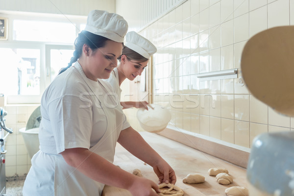 Women in bakery forming raw dough to pretzels Stock photo © Kzenon