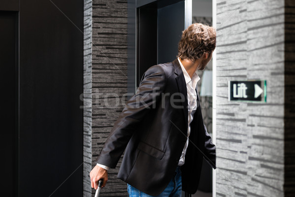 Young guest with luggage entering hotel room Stock photo © Kzenon