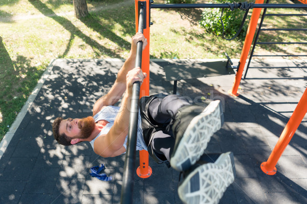 Strong man doing hanging leg raises for abdominal muscles during workout Stock photo © Kzenon