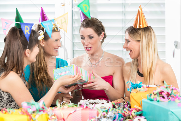 Cheerful woman holding a gift box during a surprise birthday party Stock photo © Kzenon