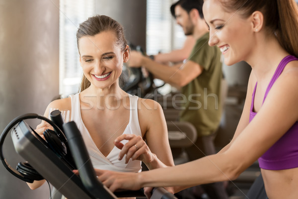 Young woman helping her friend to set the treadmill Stock photo © Kzenon