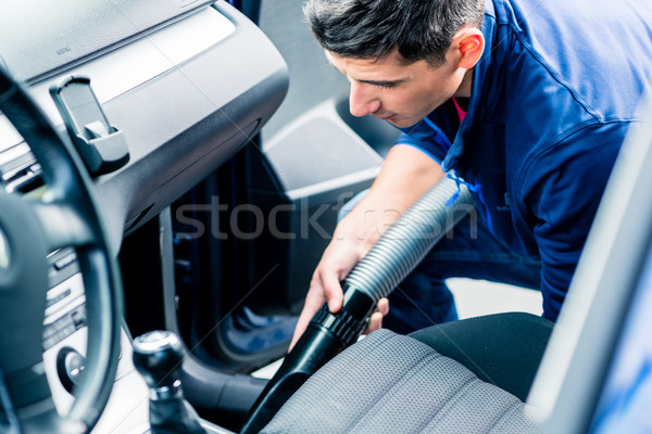 Young man using vacuum for cleaning the interior of a car  Stock photo © Kzenon