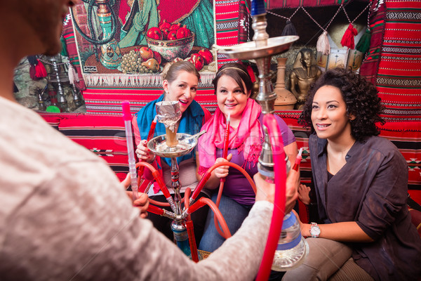 Stock photo: Group on women and men being served a hookah in shisha cafe