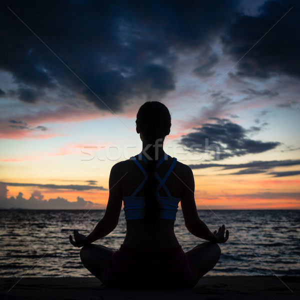 Fit woman sitting in lotus position while practicing yoga on the beach Stock photo © Kzenon