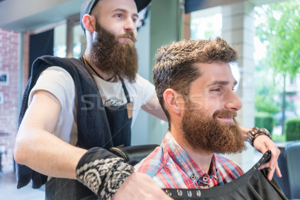 Handsome young bearded man smiling before having a trendy haircu Stock photo © Kzenon