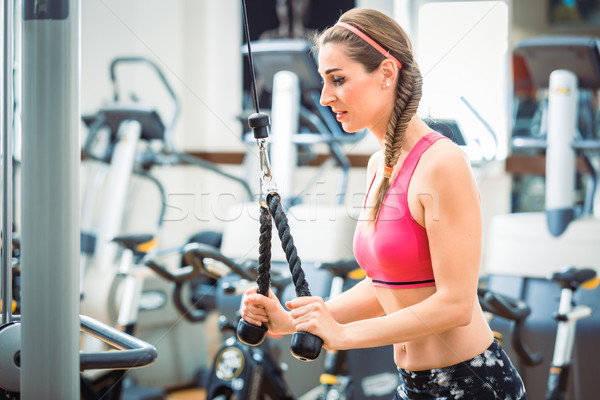 Happy fit woman wearing pink fitness bra while exercising with cable rope Stock photo © Kzenon