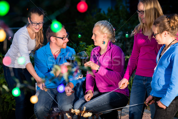 Family grilling bread on a stick at barbeque Stock photo © Kzenon