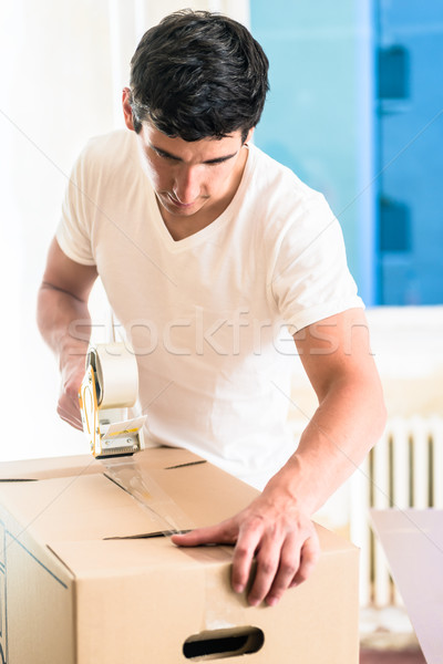 Man or handyman taping packing case Stock photo © Kzenon