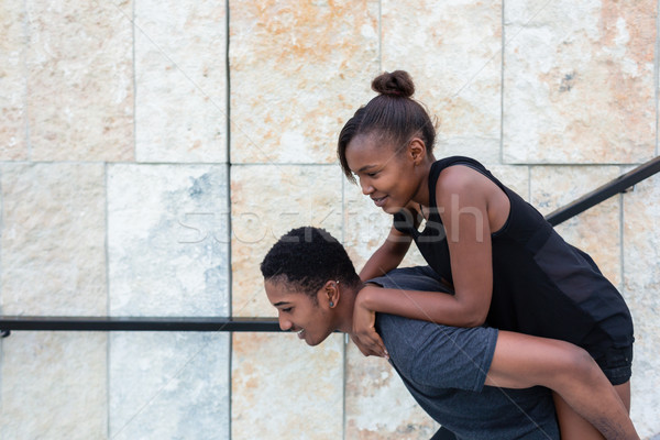 Funny young man carrying his girlfriend on back while descending Stock photo © Kzenon