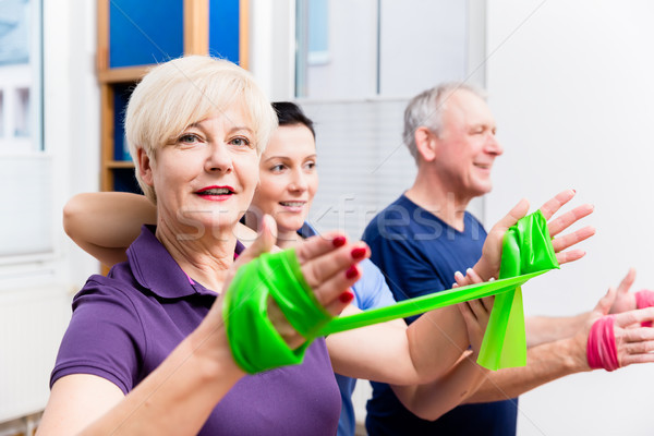 Physio showing senior couple how to use rubber band as expander Stock photo © Kzenon