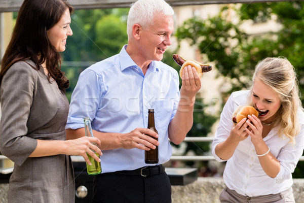 Colleagues having sausages and beer after work Stock photo © Kzenon