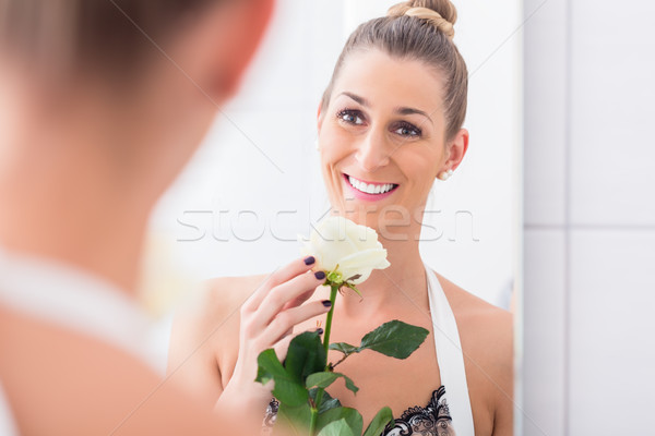 Woman holding white rose regarding herself in the mirror Stock photo © Kzenon